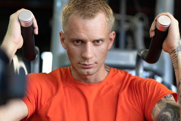 Retrato de hombre atractivo atleta guapo bombeo de los músculos en el gimnasio. entrenamiento de chico musculoso. estilo de vida activo y saludable.