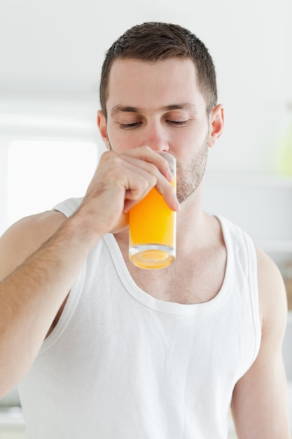 Retrato de un hombre atractivo bebiendo jugo de naranja