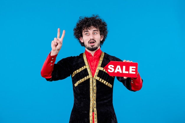 Retrato de hombre azerí posando en traje tradicional con placa de venta sobre fondo azul compras primavera étnica novruz