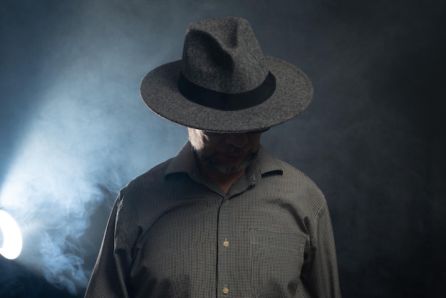 Retrato de un hombre con barba, gafas de sol y sombrero posando para la fotografía