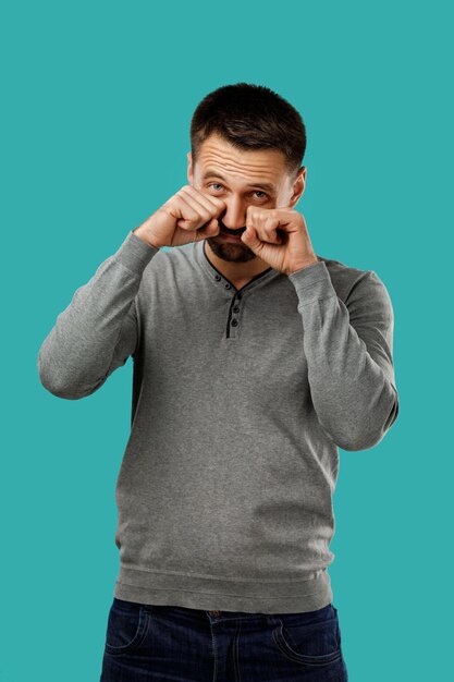 Foto retrato de un hombre de barba graciosa llorando y limpiando las lágrimas