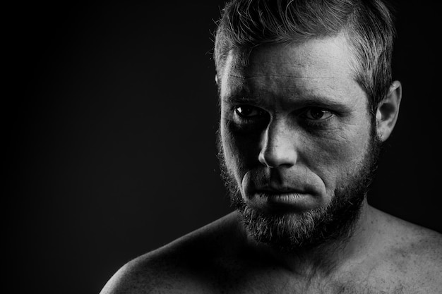 Retrato de un hombre con barba sobre un fondo negro.