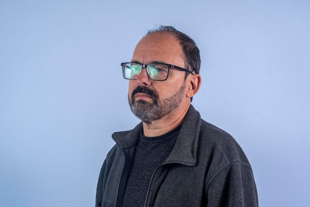 Retrato de hombre barbudo de 60 años sobre fondo azul con sombrero y gafas