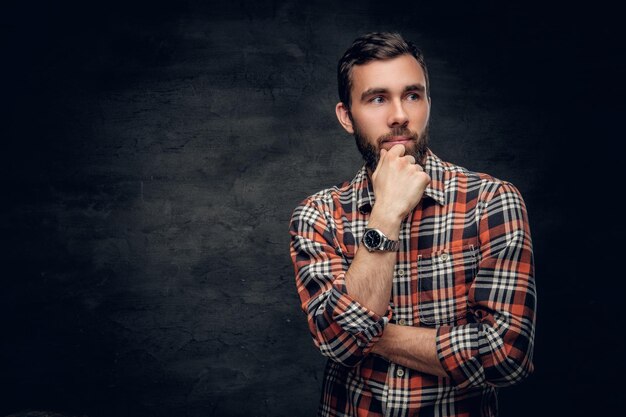 Retrato de un hombre barbudo con una camisa a cuadros roja.