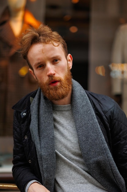 Retrato de un hombre barbudo con estilo contra el fondo de la elegante ventana de la tienda de ropa