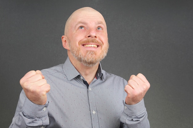 Retrato de un hombre barbudo feliz en una camisa con los brazos levantados