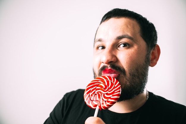 Foto retrato de hombre barbudo con gafas con lollipop rojo redondo