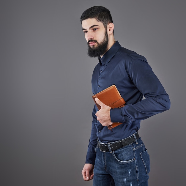 Retrato de hombre barbudo guapo dentudo con libro en las manos.