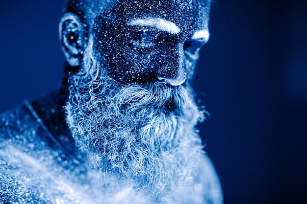 Retrato de un hombre barbudo. El hombre está pintado con polvo ultravioleta.