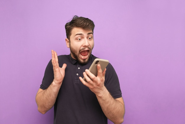 Retrato de un hombre barbudo loco con un teléfono inteligente en sus manos