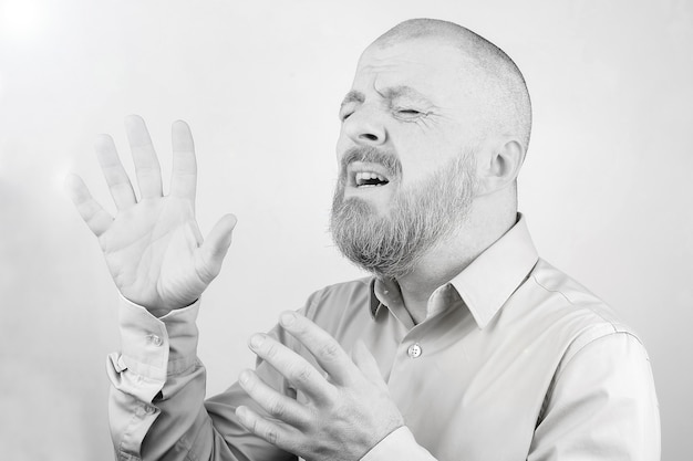 Retrato de un hombre barbudo con las manos levantadas con emociones sobre un fondo claro