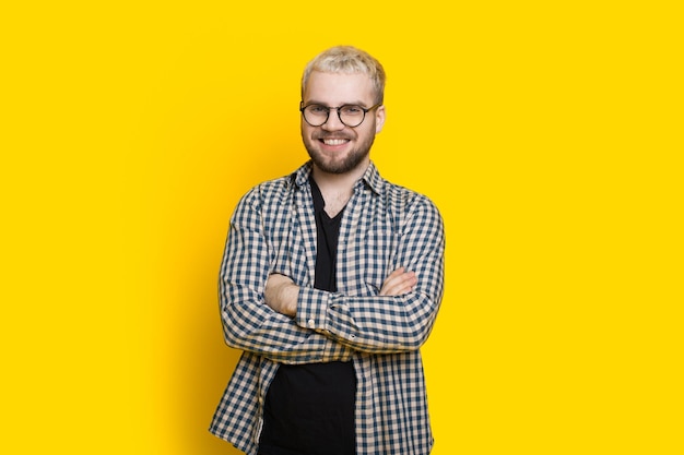 Retrato de un hombre barbudo sonriente con gafas posando con los brazos cruzados mirando a la cámara ...