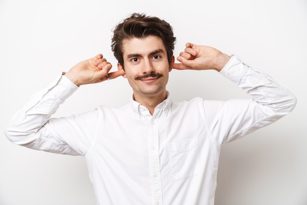 Retrato de hombre con bigote caucásico vistiendo camisa mirando al frente y tapándose los oídos aislado en blanco