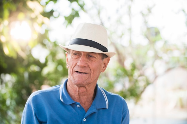 Retrato de hombre brasileño senior con sombrero blanco mirando un punto en la puesta de sol y serio. Forma horizontal, copie el espacio.