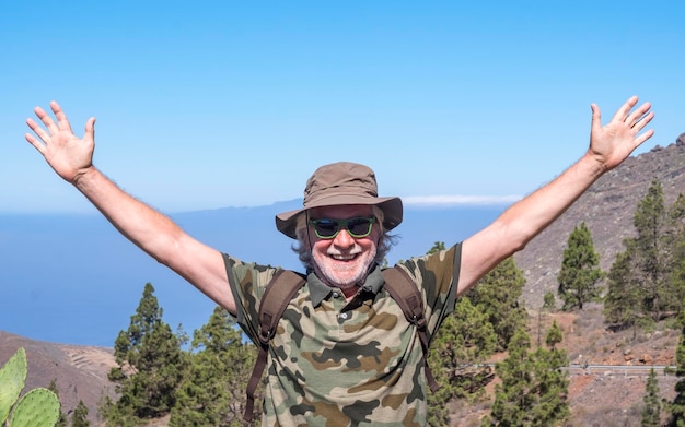 Foto retrato de un hombre con los brazos levantados contra un cielo despejado