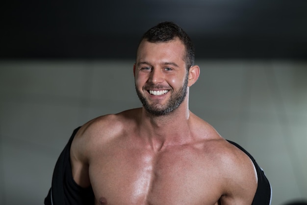 Retrato de un hombre en buena forma física que muestra su cuerpo bien entrenado en el gimnasio