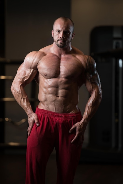 Retrato de un hombre en buena forma física que muestra su cuerpo bien entrenado Muscular culturista atlético modelo de fitness posando después de los ejercicios