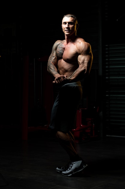 Retrato de un hombre en buena forma física que muestra su cuerpo bien entrenado Muscular culturista atlético modelo de fitness posando después de los ejercicios