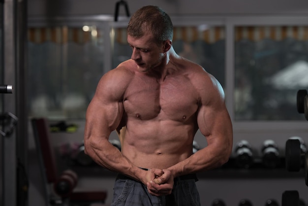 Retrato de un hombre en buena forma física que muestra su cuerpo bien entrenado Muscular culturista atlético modelo de fitness posando después de los ejercicios