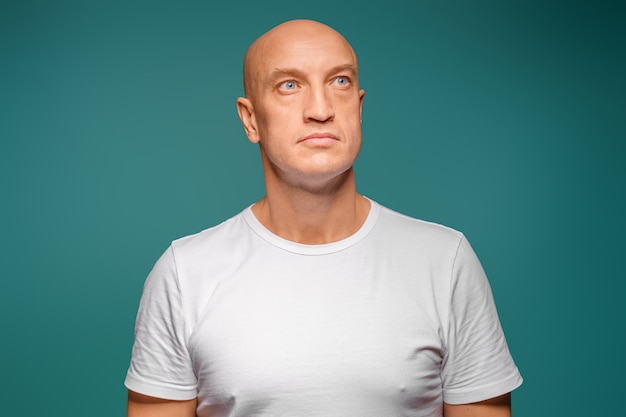 Foto retrato de un hombre calvo con una camiseta blanca en la expresión facial