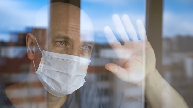 Retrato de un hombre calvo con una máscara protectora mirando por la ventana