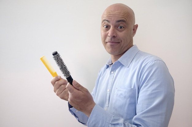 Foto retrato de un hombre calvo sonriente sosteniendo un peine