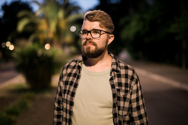 Retrato de hombre camina en la calle de la ciudad de noche con luces de la calle bokeh en segundo plano confiado solitario g