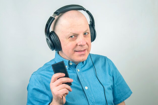 Retrato de un hombre con una camisa azul con auriculares en relajación escuchando música