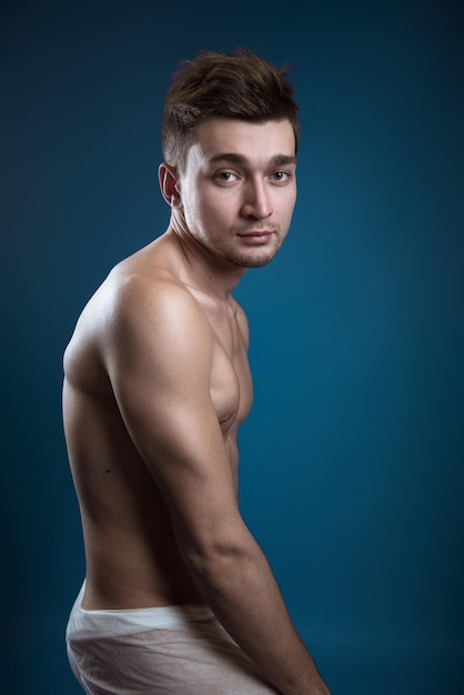 Retrato de un hombre sin camisa contra un fondo azul
