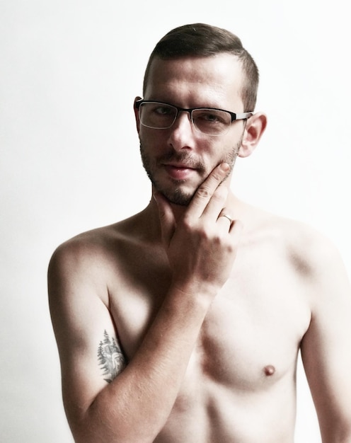 Foto retrato de un hombre sin camisa con gafas contra un fondo blanco