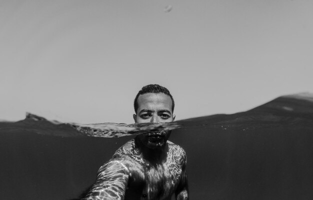 Foto retrato de un hombre sin camisa en el mar contra un cielo despejado