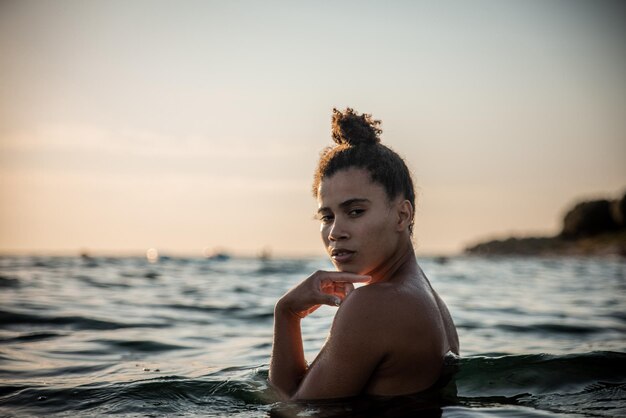 Retrato de un hombre sin camisa mirando al mar contra el cielo durante la puesta de sol