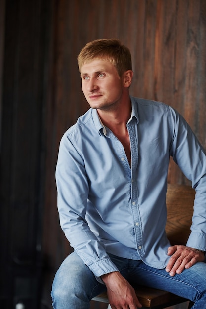 Retrato de hombre en camisa oficial que posa para la cámara en el interior.