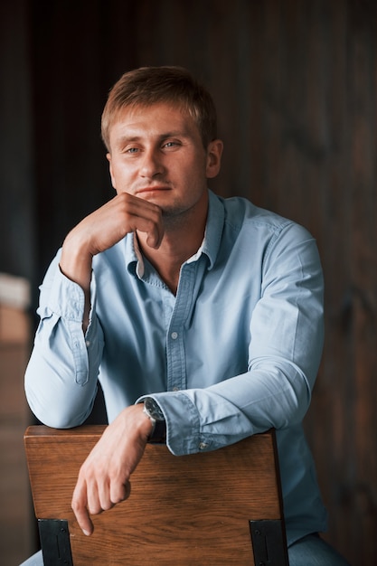 Retrato de hombre en camisa oficial que posa para la cámara en el interior.