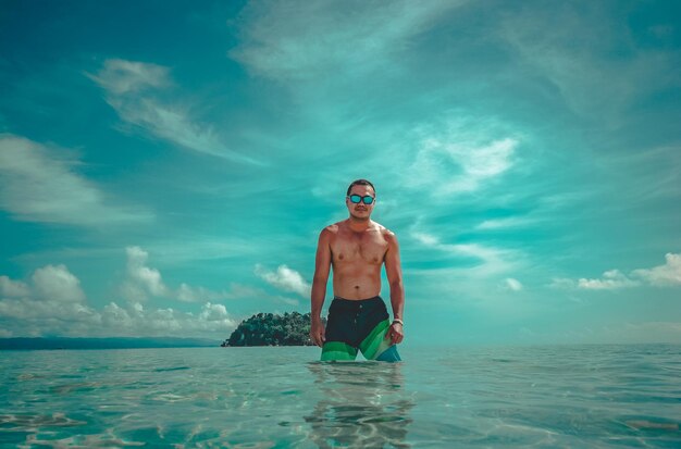 Foto retrato de un hombre sin camisa de pie en el mar contra el cielo