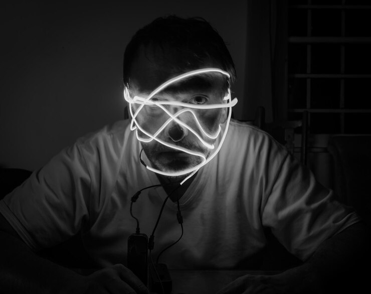 Foto retrato de un hombre con la cara brillante sentado en un cuarto oscuro