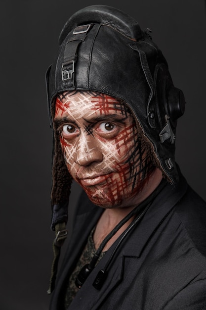Retrato de un hombre con la cara pintada y la cabeza cubierta contra un fondo gris