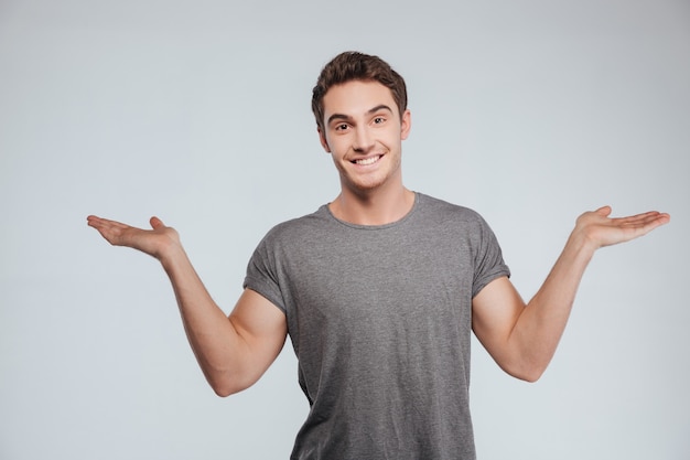 Retrato de un hombre casual sonriente sosteniendo copyspace en dos palmas en blanco