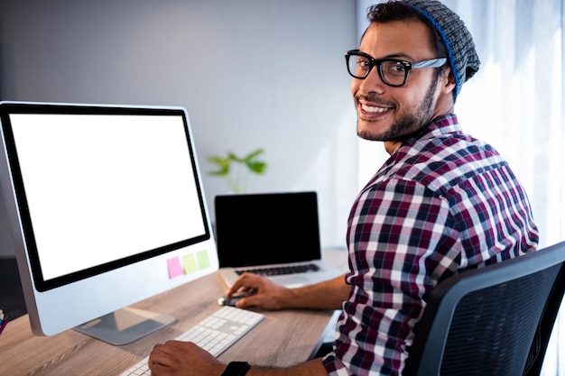 Retrato de hombre casual trabajando en el escritorio de la computadora