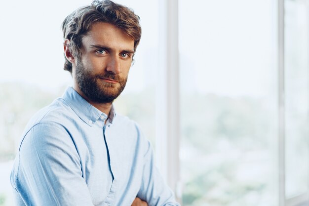 Retrato de un hombre caucásico en camisa casual de pie cerca de la ventana. Hombre de negocios, retrato