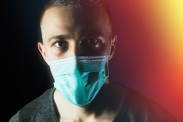 Retrato de hombre caucásico en una máscara de gasa médica sobre fondo azul oscuro Prevención del virus covid19