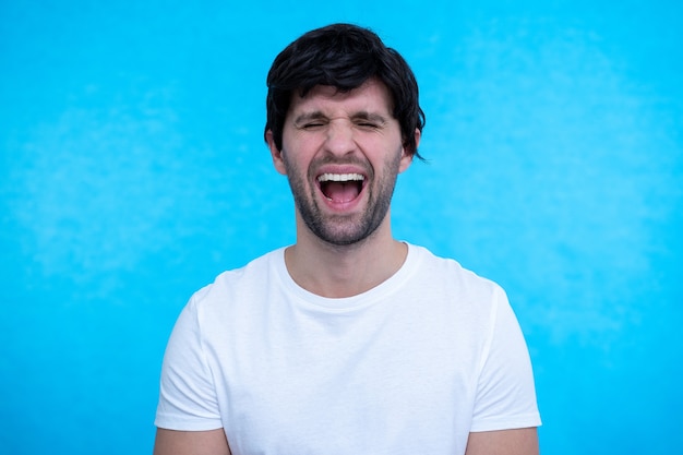 Retrato de hombre de cerca, el chico está conmocionado, extremadamente feliz, con los ojos bien abiertos y la boca en la superficie azul