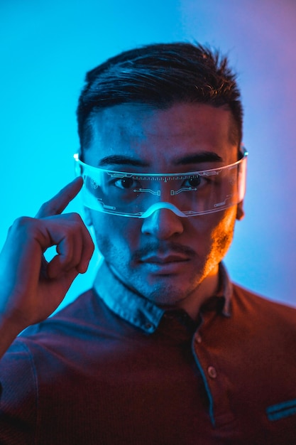 Retrato de hombre chino con gafas de neón con tecnología de concepto futurista de luz azul y naranja de ciberhumanos