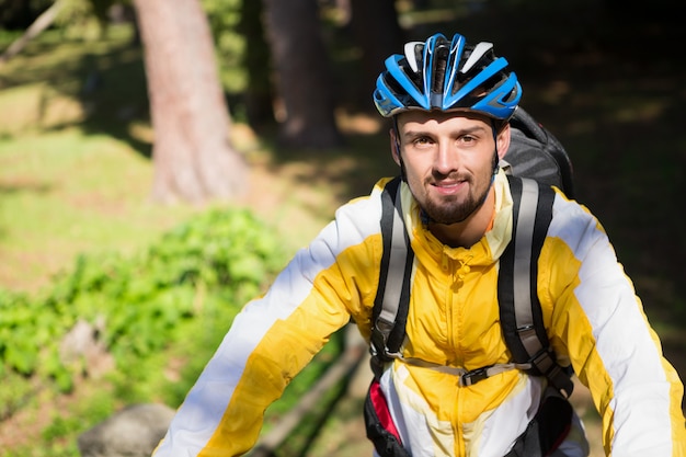 Retrato de hombre ciclista de montaña con bicicleta en el bosque