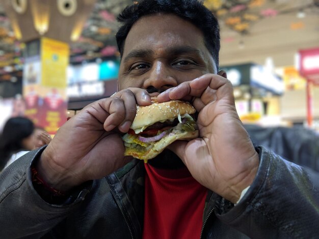 Retrato de un hombre comiendo una hamburguesa en un restaurante