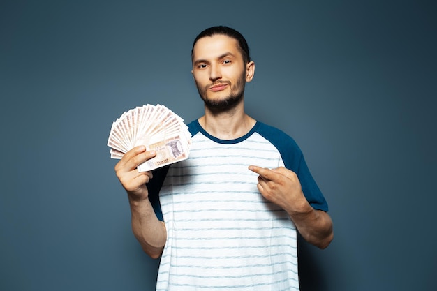 Retrato de un hombre confiado sosteniendo dinero apuntando con el dedo a los billetes leu moldavo