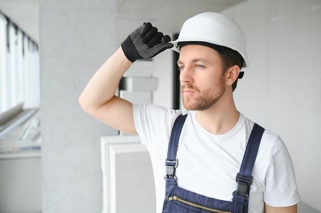 Retrato de un hombre constructor positivo de pie en un apartamento