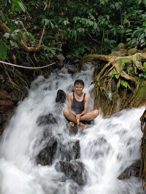 Retrato de un hombre contra una cascada en el bosque