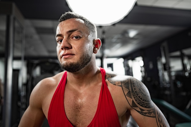 Retrato de hombre culturista en camisa roja en el gimnasio