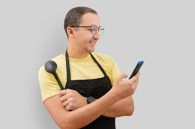 Retrato de un hombre en un delantal y un teléfono en la mano sobre un fondo gris